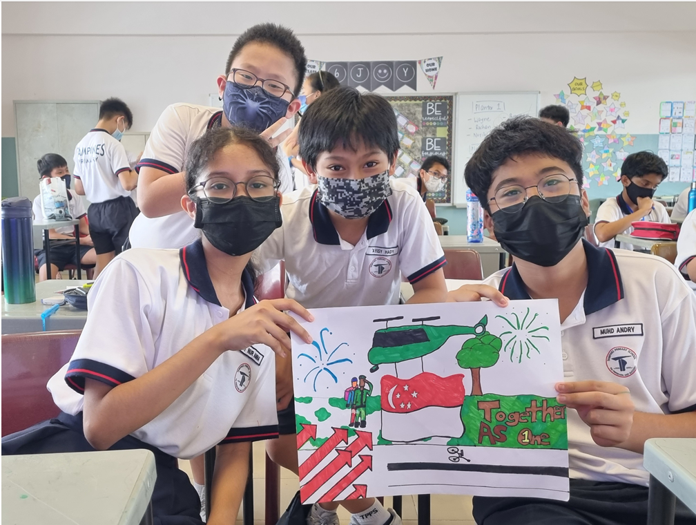 Four masked students in a classroom hold a drawing featuring the Singapore flag and the text Together As One.